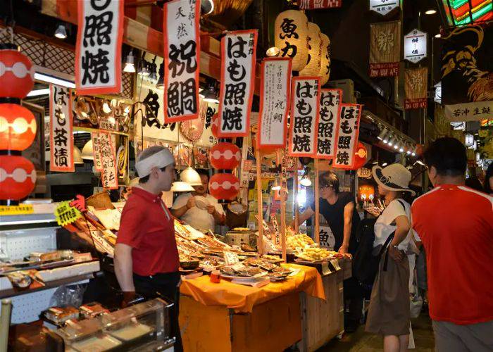 People talking to the street food vendors of Nishiki Market.